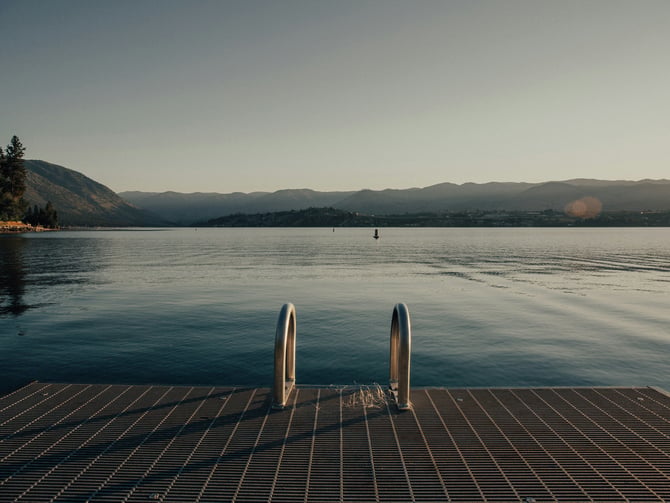 Dock ladder leading into calm lake water with mountains behind at Lake Sammamish State Park